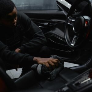 A man wipes the interior of a car for a thorough cleaning, focusing on detailing and maintenance.